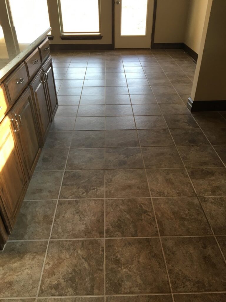 A meticulously cleaned tiled kitchen floor next to wooden cabinets by Pristine Cleaning Concepts in Stillwater, OK.
