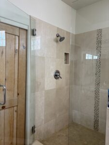 A sparkling clean shower with light-colored tiled walls and a clear glass door, maintained by Carole's House Cleaning in Tempe, AZ.
