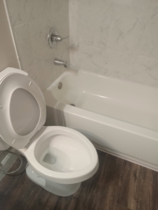 A freshly cleaned toilet and bathtub in a modern bathroom, demonstrating the thorough house cleaning by Dacari's Helping Hands LLC in South Bend, IN.