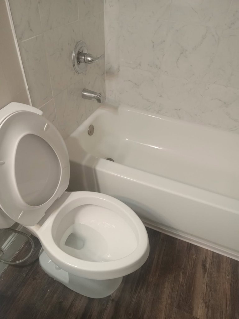A freshly cleaned toilet and bathtub in a modern bathroom, demonstrating the thorough house cleaning by Dacari's Helping Hands LLC in South Bend, IN.