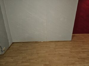 A close-up view of a clean wood-paneled wall and polished wood floor, showcasing attention to detail by Way Too Bright Services LLC in Rockford, IL.