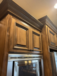 Sparkling clean wooden kitchen cabinets above a microwave, cleaned by Cleaning by Design LLC in Frederick, MD.