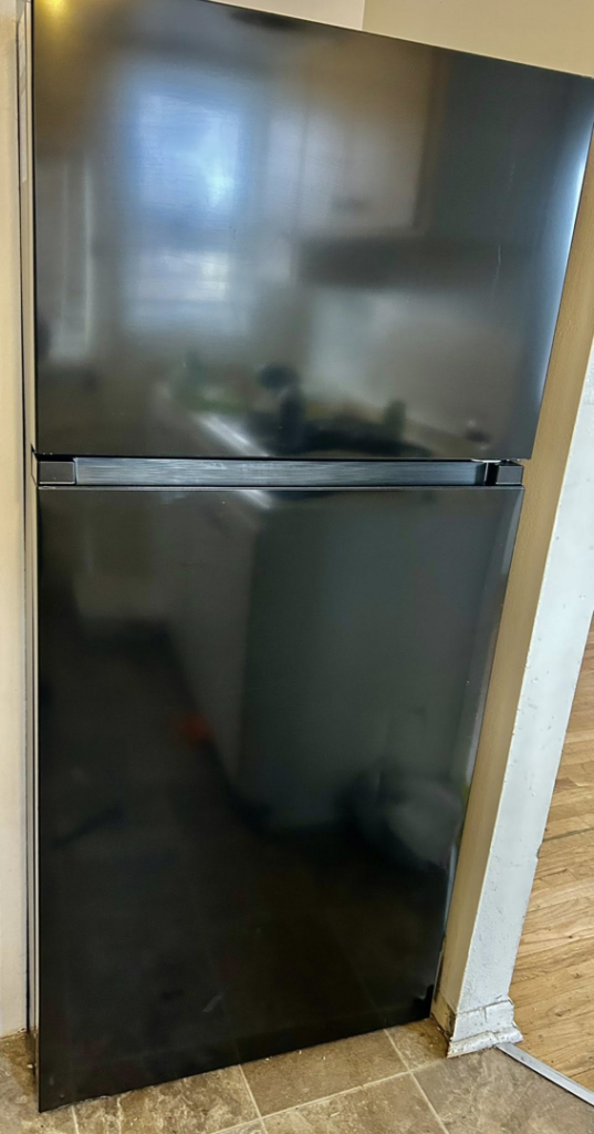 A sparkling clean black refrigerator in a kitchen, showcasing the detailed appliance cleaning service by Elite A&C Cleaning, LLC in Casper, WY.