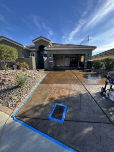 A freshly cleaned residential driveway with protective blue tape by Farki Pressure Washer LLC in Mesquite, NV