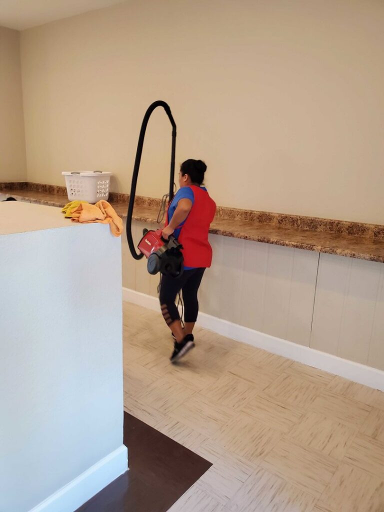 A professional house cleaner carrying a backpack vacuum cleaner for Arizona Housekeeping Service in Phoenix, AZ.