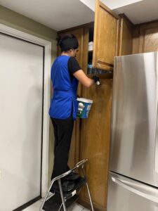 A cleaner from Fabylous Cleaning Service cleaning upper kitchen cabinets in Anaheim, CA.