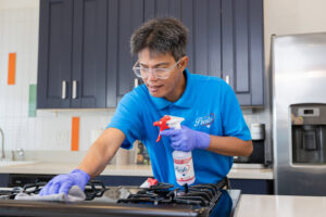 A professional cleaner from Presto Cleaning cleaning a kitchen stovetop in San Diego, CA.