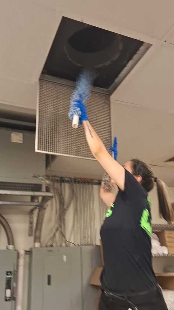 A cleaner from Absolute Luxury, LLC Residential & Commercial Cleaning uses a duster to clean a ceiling vent in Antioch, TN.