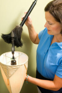 A house cleaner carefully dusting a lamp, showcasing services from Mid Atlantic Maid Service of Richmond, VA.