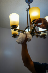 A cleaner from Southern Royalty Cleaning service carefully dusting a light fixture in a home in Chesapeake, VA.