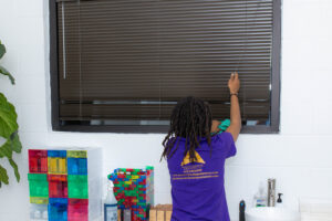 A house cleaner from Ascent Cleaning Solutions, LLC dusting window blinds in a home in Nashville, TN
