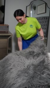 A professional cleaner from Picky Performance Cleaning neatly folding a fluffy rug in a bedroom in North Las Vegas, NV