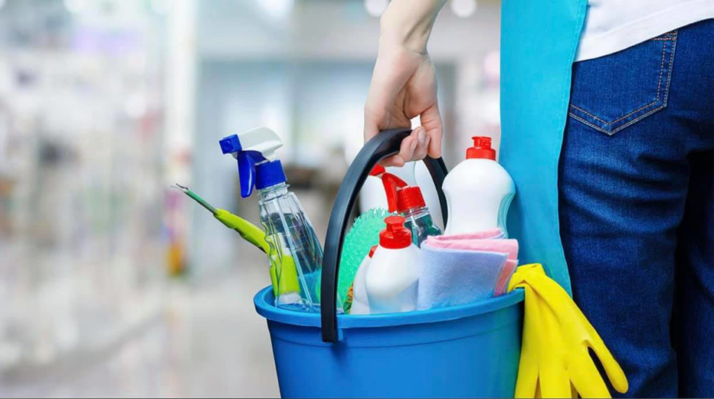 A house cleaner holding a blue bucket filled with various cleaning supplies for Milwaukee Cleaning Services in Milwaukee, WI.