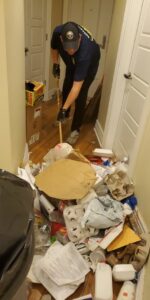 A cleaner from City Cleaning Crew in Buffalo, NY, removing trash from a very messy room during a deep clean.