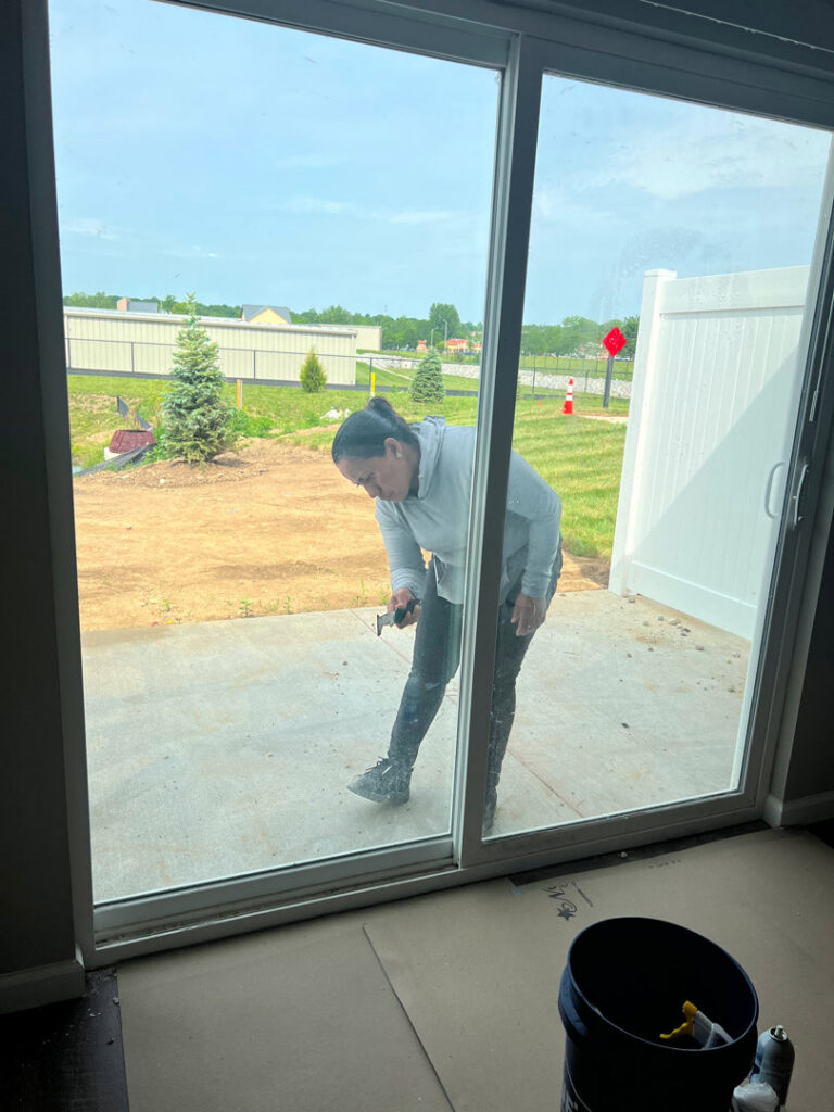 A cleaner from Gem City Commercial and Residential Cleaning scraping a glass sliding door in a residential setting in Dayton, OH