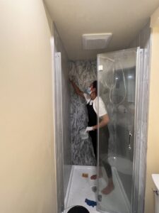 A cleaner from Bivian's Cleaners LLC scrubbing a shower in a bathroom in Trenton, NJ.