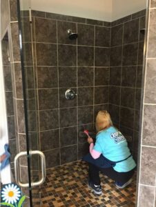 A cleaner scrubbing shower tiles with a brush for Fresh Clean Wave in Columbia, SC.