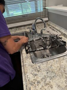 A professional cleaner from 3K Cleaning Service scrubbing a stovetop grate in a kitchen sink in Philadelphia, PA.