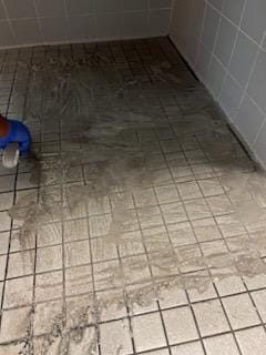 A cleaner from Arroyos Cleaning LLC scrubbing a dirty tiled shower floor in Fort Myers, FL.