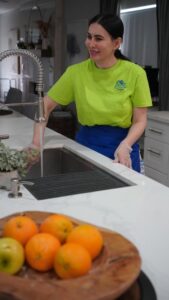A friendly cleaner from Picky Performance Cleaning smiling while working by a kitchen sink in North Las Vegas, NV