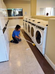 A house cleaner sweeping the floor in a commercial laundry room for Arizona Housekeeping Service in Phoenix, AZ.