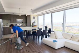 A professional cleaner from Supreme Home Cleaning, Inc vacuuming an apartment with a view of the city in Boston, MA.