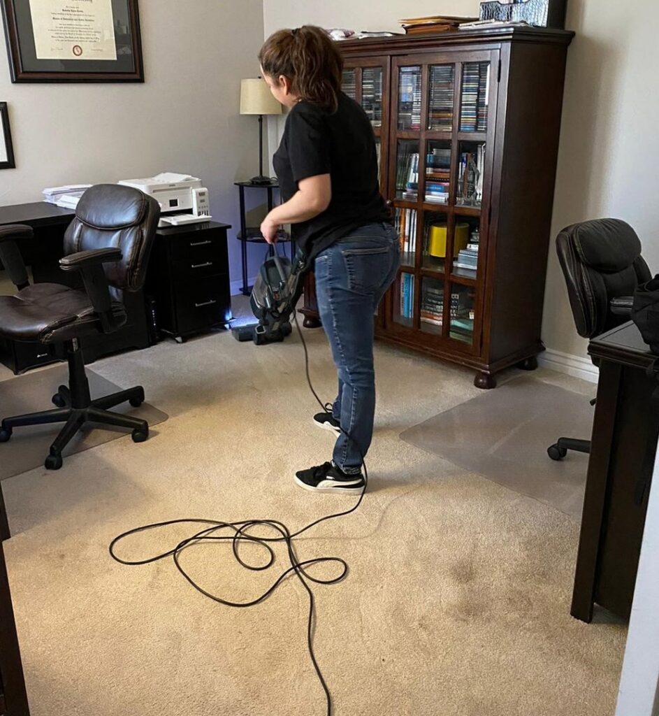 A house cleaner from Denver MOP STARS Cleaning Service vacuuming a carpeted room in Denver, CO.