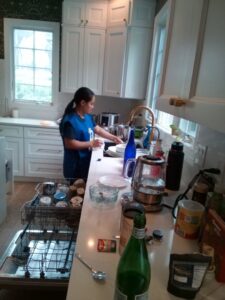 A cleaner from Bivian's Cleaners LLC washing dishes in a kitchen sink in Trenton, NJ.
