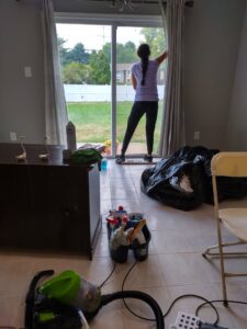 A cleaner from Bivian's Cleaners LLC washing a glass sliding door in a home in Trenton, NJ.