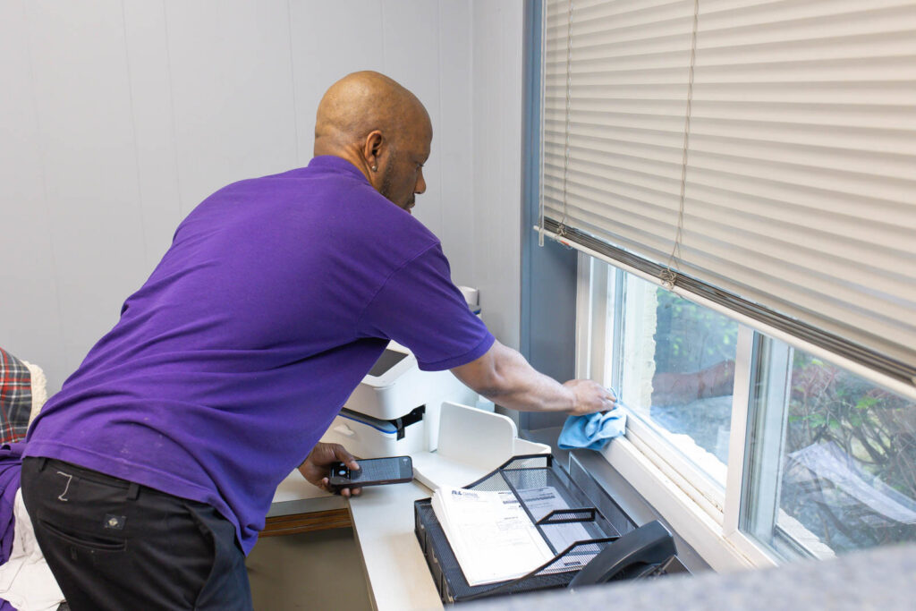 A house cleaner from Ascent Cleaning Solutions, LLC washing a window in a home in Nashville, TN