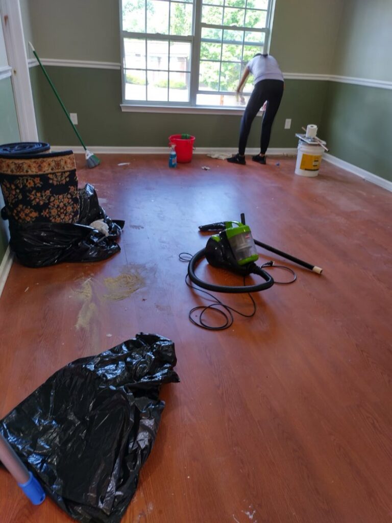 A cleaner from Bivian's Cleaners LLC washing a window in a room in Trenton, NJ.