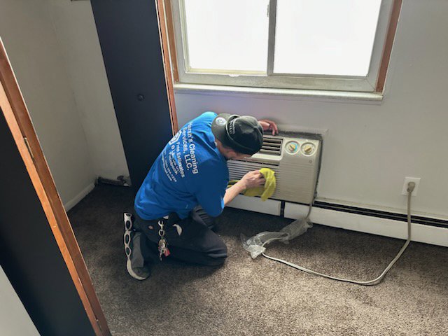 A cleaner from Harsh's Cleaning Services LLC wiping down an air conditioning unit in a home in Canton, OH.
