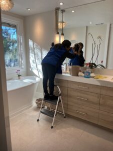 A cleaner from Fabylous Cleaning Service wiping a large bathroom mirror in Anaheim, CA.