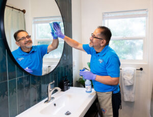 A professional cleaner from Presto Cleaning wiping a bathroom mirror in San Diego, CA.