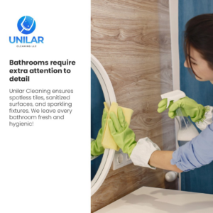 A cleaner wearing green gloves, spraying and wiping a bathroom mirror with a yellow cloth for Unilar Cleaning LLC in Pittsburgh, PA.
