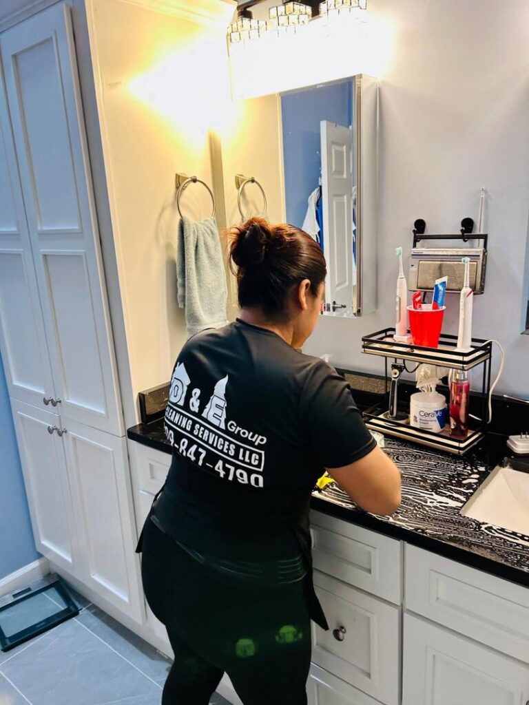 A professional cleaner from D&E Cleaning Group wiping down a bathroom vanity in a home in Pittsburgh, PA.