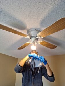 A cleaner from Absolute Luxury, LLC Residential & Commercial Cleaning meticulously wipes down a ceiling fan in Antioch, TN.