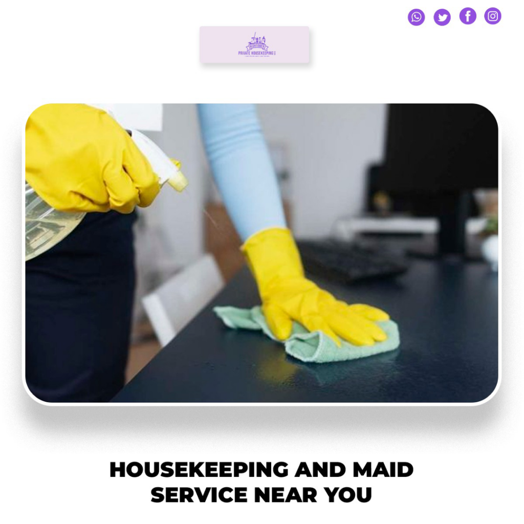A cleaner wearing yellow gloves spraying and wiping a desk surface for Hightower Private Housekeeping in Henderson, NV.