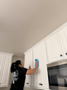 A cleaner from Ríos cleaning services wiping down kitchen cabinets in a home in Greeley, CO.