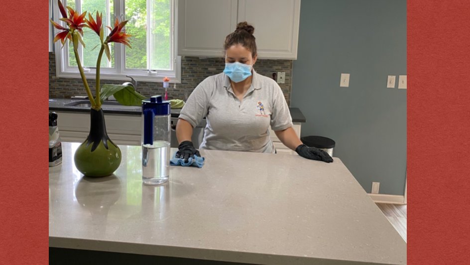 A cleaner from Bivian's Cleaners LLC wiping a kitchen counter with a cloth in Trenton, NJ.
