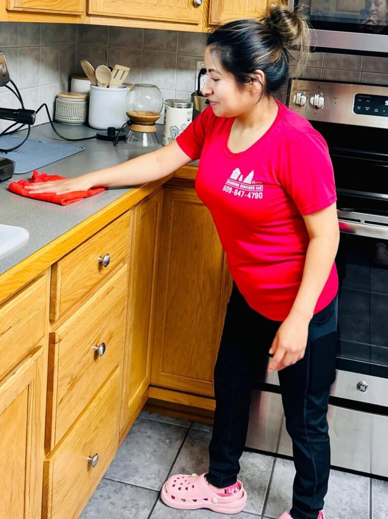 A professional cleaner from D&E Cleaning Group wiping a kitchen counter in Pittsburgh, PA.