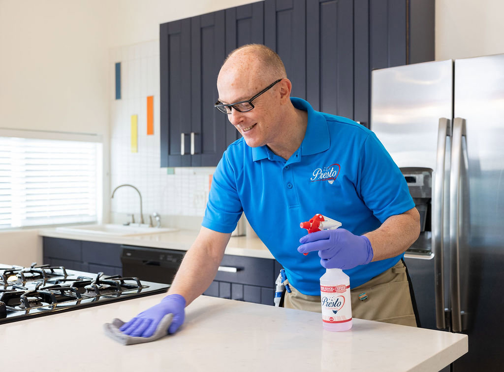 A professional cleaner from Presto Cleaning wiping a kitchen counter in San Diego, CA.