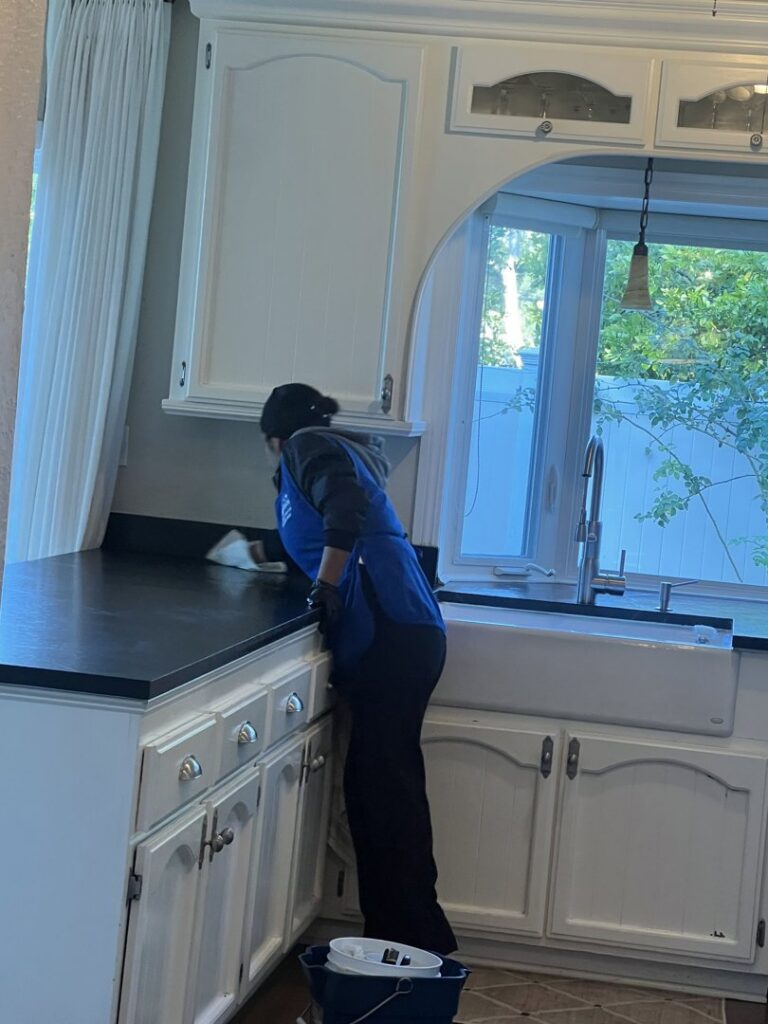 A cleaner from Fabylous Cleaning Service wiping a kitchen countertop in Anaheim, CA.