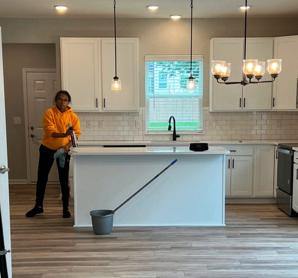 A cleaner from Gem City Commercial and Residential Cleaning wiping down a kitchen island with a spray bottle and cloth in Dayton, OH