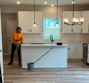 A cleaner from Gem City Commercial and Residential Cleaning wiping down a kitchen island with a spray bottle and cloth in Dayton, OH