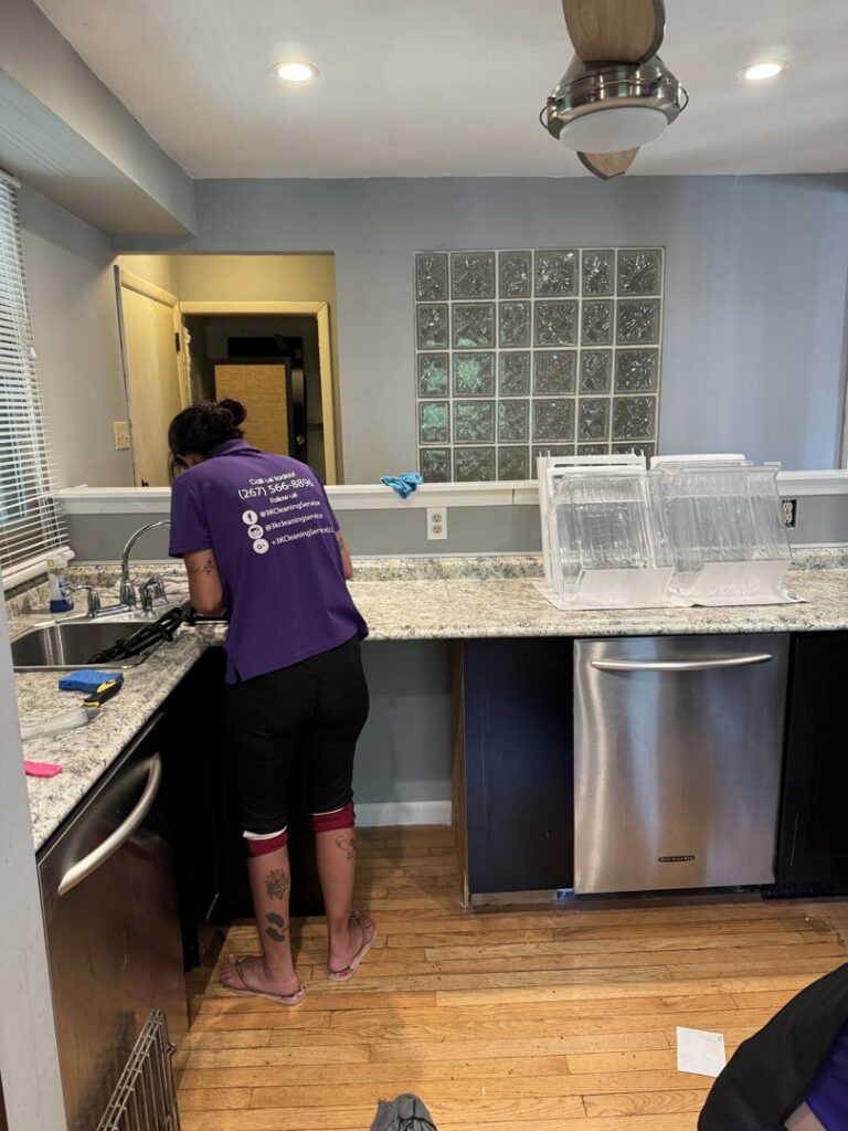 A cleaner from 3K Cleaning Service wiping down a kitchen sink and countertop in Philadelphia, PA.
