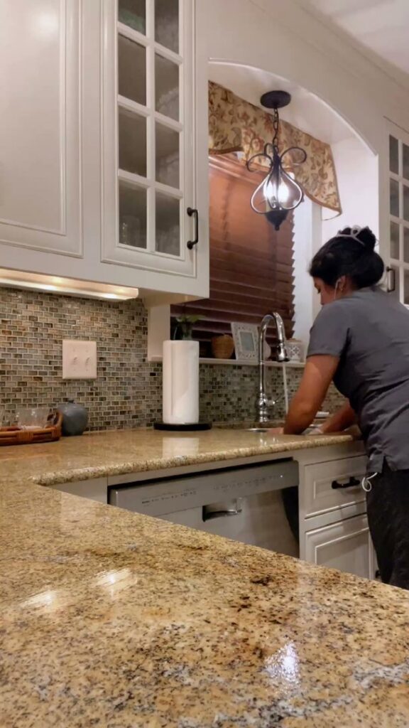 A professional house cleaner from Ruby Cleaning in Lafayette, LA, diligently wiping a kitchen sink.