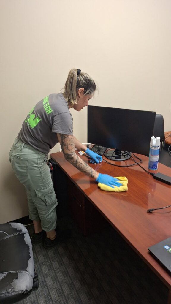 A cleaner from Absolute Luxury, LLC Residential & Commercial Cleaning wipes down an office desk in Antioch, TN.