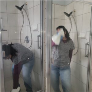 A cleaner from Dust Bunnies Cleaning Services in Bakersfield, CA, wiping down a shower enclosure.