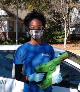 A Castle Keepers House Cleaning professional in North Charleston, SC, wearing a mask and gloves, holding an electrostatic sprayer for advanced sanitization.